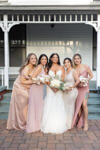 A bride and her bridesmaids in blush standing in front of the Withers Maguire House at Ocoee Lakeshore Center.