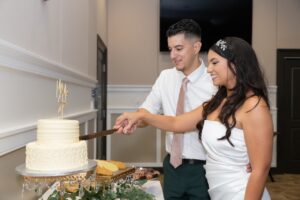 A bride and groom cut their two-tier cake inside their reception in a ballroom at Ocoee Lakeshore Center.