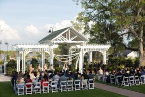 A bride and groom standing at the altar at the wedding garden outside at Ocoee Lakeshore Center surrounded by their guests.