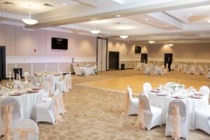 A ballroom at Ocoee Lakeshore Center ready for a white and blush pink wedding reception with circular tables and a dance floor.