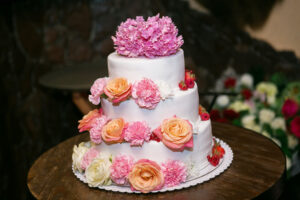 a 3-tier white cake with pink, orange and white florals.