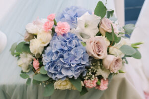 A bridal bouquet with Hydrangeas, Roses, Carnations and Baby's Breath in blue, pink and white.