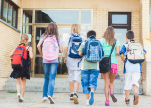 kids heading into school with their backpacks on