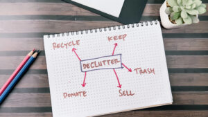 notebook that has declutter written down pointing to recycle, keep, donate, sell and trash.