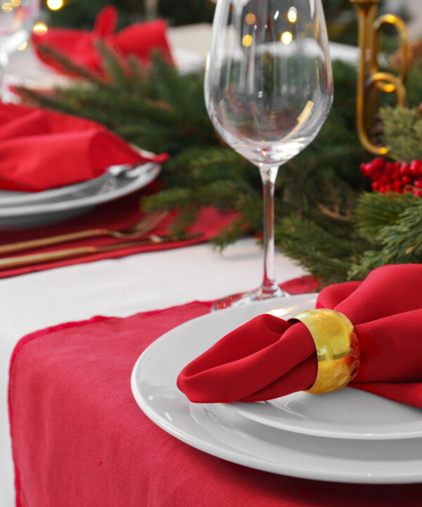 A holiday tablescape with red linen and white linen, christmas decor wine glasses.