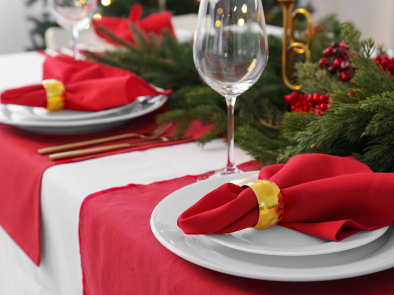 A holiday tablescape with red linen and white linen, christmas decor wine glasses.