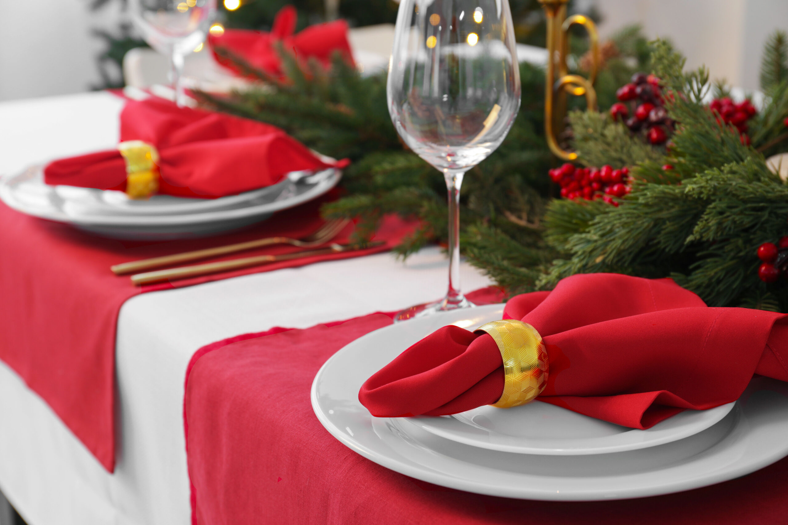 A holiday tablescape with red linen and white linen, christmas decor wine glasses.